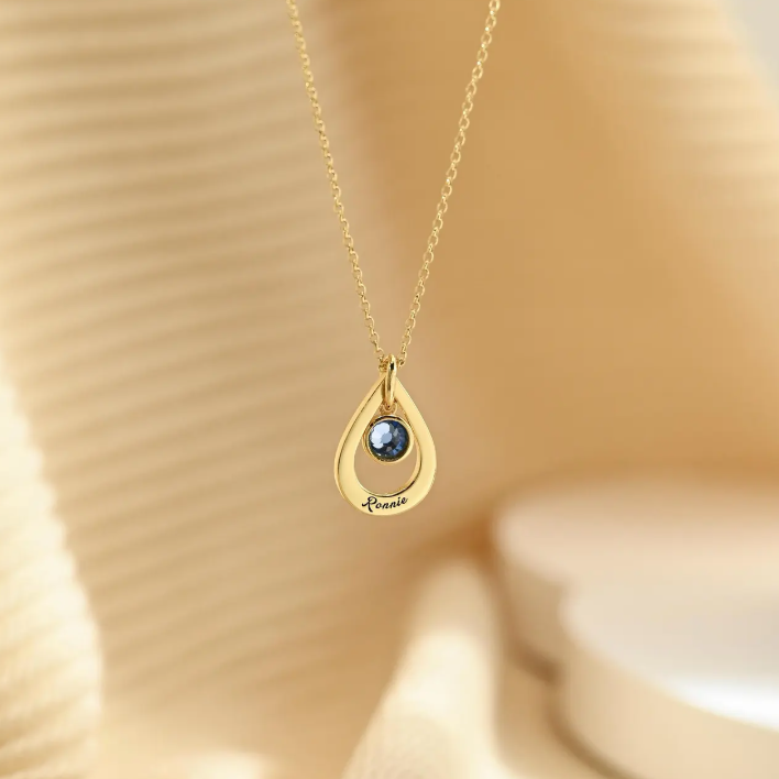 A personalized drop-style name necklace designed with a delicate birthstone-inspired accent. The flowing letter design creates an elegant and meaningful look, suitable for everyday wear or thoughtful gifting.
