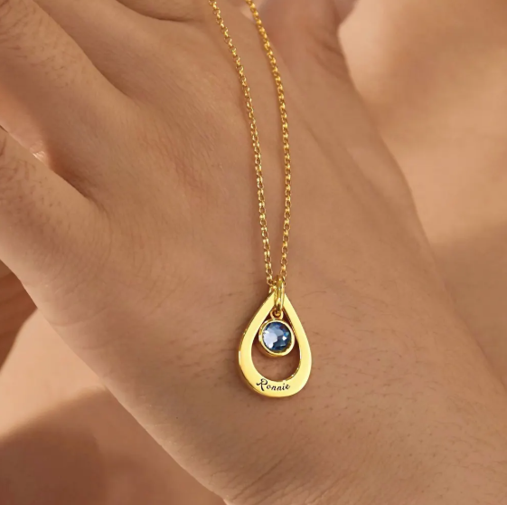 A personalized drop-style name necklace designed with a delicate birthstone-inspired accent. The flowing letter design creates an elegant and meaningful look, suitable for everyday wear or thoughtful gifting.