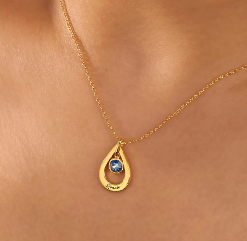 A personalized drop-style name necklace designed with a delicate birthstone-inspired accent. The flowing letter design creates an elegant and meaningful look, suitable for everyday wear or thoughtful gifting.